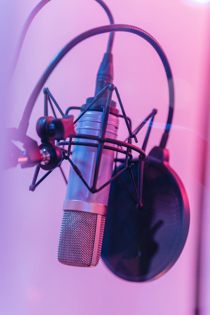 Close-up of a studio microphone with pop filter in vibrant neon lighting. Perfect for music production concepts.